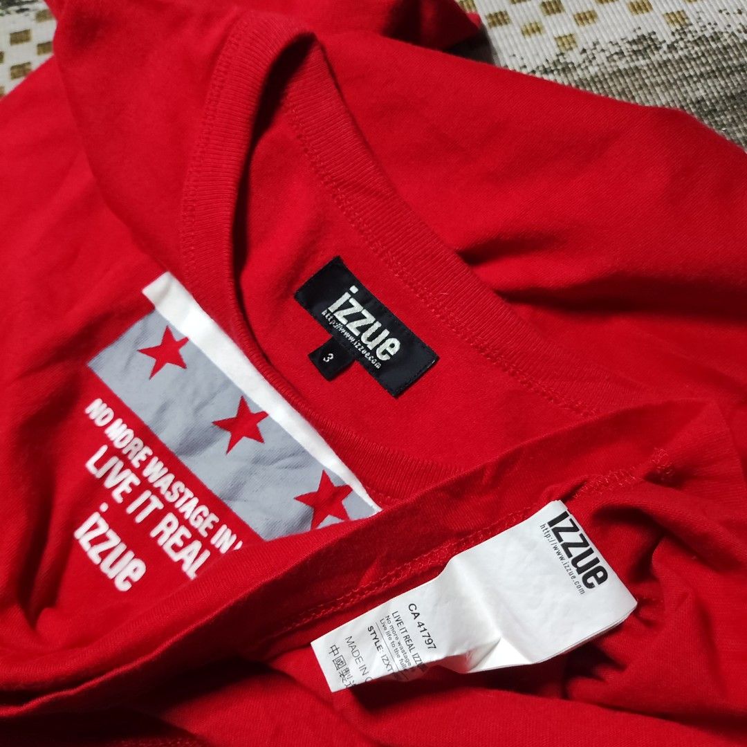 Izzue Rampage Red T-Shirt (Category: Tshirts & Polo Shirts ) located in Taguig. Submitted by althriftdailyloots94 (Listing ID 1465072360, Image 3). Description: - Brand/Style: Authentic Izzue bright red t-shirt with short sleeves and classic crew neck - Design: Large white and grey front graphic featuring 'RAMPAGE' text, motivational slogan, and red star accents - Fit & Fabric: Relaxed everyday fit made from soft, comfortable cotton - Details: In