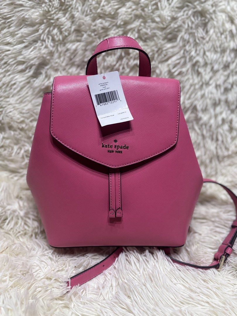 Kate Spade New York Lizzie Medium Flip Backpack (Category: Backpacks) located in Cabugao. Submitted by jezzarrogante_rmt (Listing ID 1465043243, Image 1). Description: Kate Spade Lizzie medium flip backpack available in two colors: pink and white. Structured design featuring a foldover flap closure with metal branding on the front. Includes adjustable shoulder straps and a top carry handle. Price tag attached on the pink option showing style numb