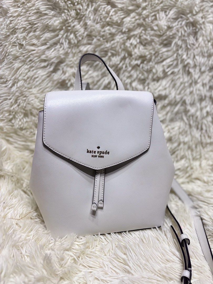Kate Spade New York Lizzie Medium Flip Backpack (Category: Backpacks) located in Cabugao. Submitted by jezzarrogante_rmt (Listing ID 1465043243, Image 2). Description: Kate Spade Lizzie medium flip backpack available in two colors: pink and white. Structured design featuring a foldover flap closure with metal branding on the front. Includes adjustable shoulder straps and a top carry handle. Price tag attached on the pink option showing style numb