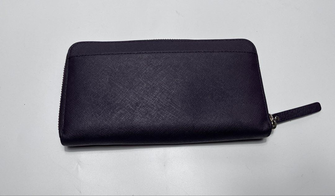 Kate Spade New York Zip Around Wallet (Category: Wallets & Card holders) located in Iloilo. Submitted by fromthebins.ilo2 (Listing ID 1465000473, Image 2). Description: - Brand: Kate Spade New York - Color: Deep purple - Material: Genuine leather with signature pink patterned fabric lining - Closure: Zip-around with a matching wrist strap - Interior Features: Multiple card slots, slip compartments, and a zippered coin pocket - Exterior: Gold meta
