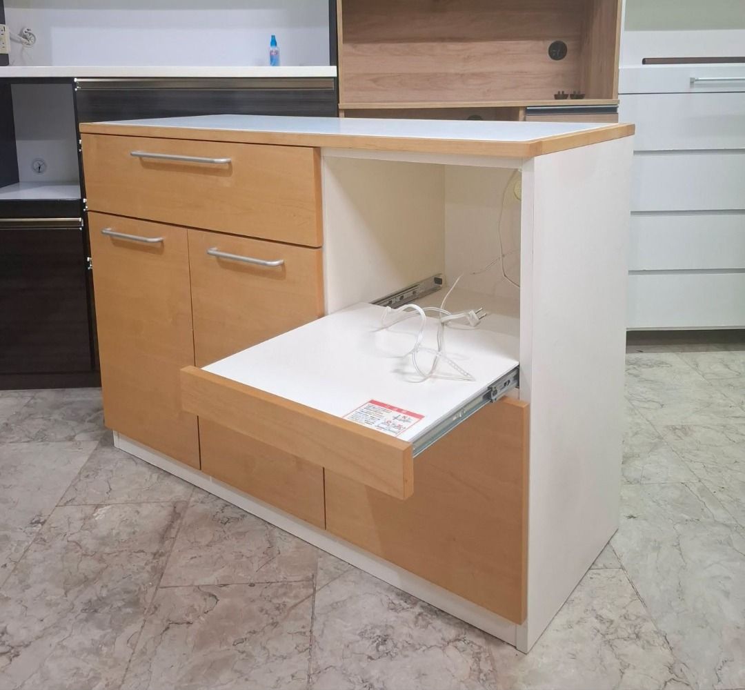 Kitchen Island Cabinet with Pull-out Shelf and Storage (Category: Shelves, Cabinets & Racks) located in Quezon City. Submitted by japandemanila (Listing ID 1465007655, Image 2). Description: - Elegant wooden and white kitchen island unit - Smooth countertop surface for extra prep space - Convenient pull-out appliance shelf with built-in power outlets - Includes a top drawer, spacious double-door cabinet, and a lower drawer - Sturdy build with a c