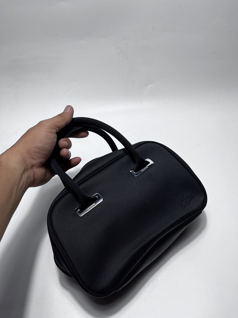 Lacoste Black Handbag (Category: Tote Bags) located in Iloilo. Submitted by fromthebins.ilo2 (Listing ID 1464969467, Image 3). Description: - Brand: Lacoste - Color: Classic Black - Material: Durable textured nylon with silver-tone hardware - Design: Structured shape with sturdy twin handles and debossed crocodile logo - Closure: Secure double zip top closure - Condition: Clean stitching throughout, well-maintained / Excellent or no issues - Size