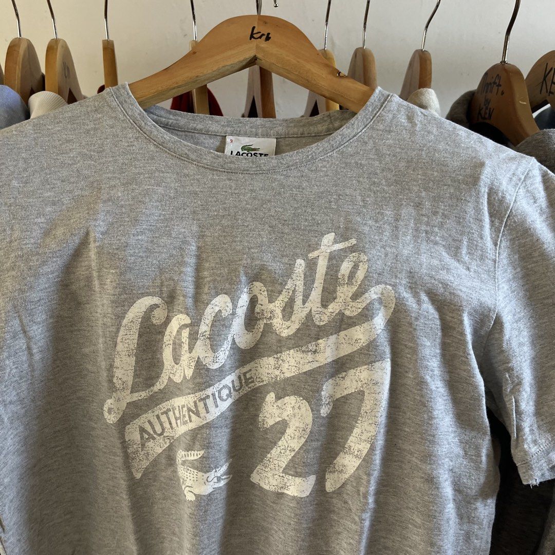 Lacoste Grey Graphic T-Shirt Size 3 (Category: Tshirts & Polo Shirts ) located in Sagbayan (Borja). Submitted by lunapawpaw46843 (Listing ID 1465048372, Image 3). Description: - Brand: Lacoste - Style: Crew neck tee with distressed front graphic - Size: 3 (fits standard) - Color: Grey - Material: Comfortable cotton blend - Design details: Large 'Authentique', '27', and logo print (distressing is part of original design) - Condition: Great everyda
