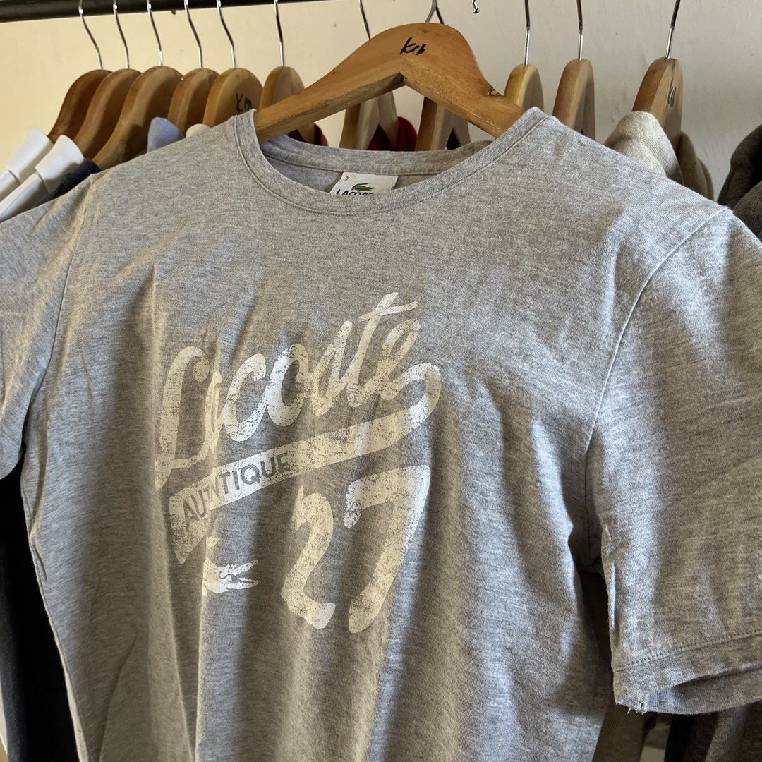 Lacoste Grey Graphic T-Shirt Size 3 (Category: Tshirts & Polo Shirts ) located in Sagbayan (Borja). Submitted by lunapawpaw46843 (Listing ID 1465048372, Image 2). Description: - Brand: Lacoste - Style: Crew neck tee with distressed front graphic - Size: 3 (fits standard) - Color: Grey - Material: Comfortable cotton blend - Design details: Large 'Authentique', '27', and logo print (distressing is part of original design) - Condition: Great everyda