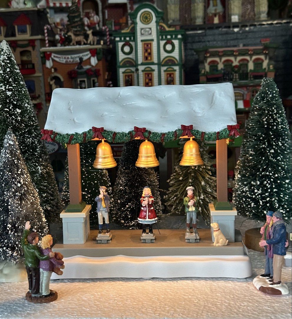 Lemax Bells Are Ringing animated (Category: Figurines & Statues) located in Santiago. Submitted by kitalpanga (Listing ID 1465058360, Image 2). Description: Animated. With sounds, light and movement - Festive holiday village miniature featuring three children ringing gold bells - Decorated with green garland, red bows, and a cute yellow dog - Detailed painted resin construction on a snowy base - Perfect addition to Christmas mantel displays and h