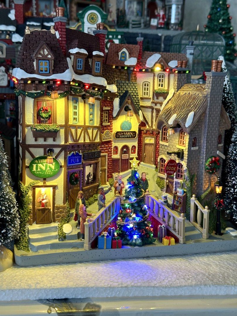 Lemax Oxfordshire Village (Category: Figurines & Statues) located in Santiago. Submitted by kitalpanga (Listing ID 1465066251, Image 2). Description: Battery operated / 4.5v adaptable - Detailed Christmas village scene complete with the Village Inn, Yarn Shoppe, and David's Book Store - Features a glowing center Christmas tree and warm lit windows - Includes miniature figurines walking across the bridge and streets - Designed with intricate brick