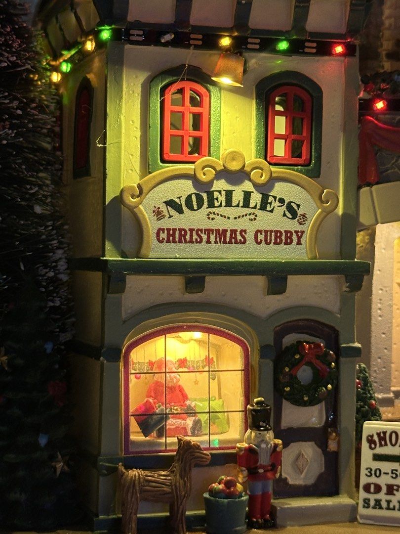 Lemax Tis The Season Shops Facade (Category: Figurines & Statues) located in Santiago. Submitted by kitalpanga (Listing ID 1465066054, Image 3). Description: Battery operated / 4.5v adaptable - Festive multi-story Christmas village design - Features colorful shops, a wine bar, nutcracker, wreaths, and holiday signs - Lights up with a large glowing tree and warm window lights - Crafted from durable, heavy resin - Perfect holiday centerpiece for ma