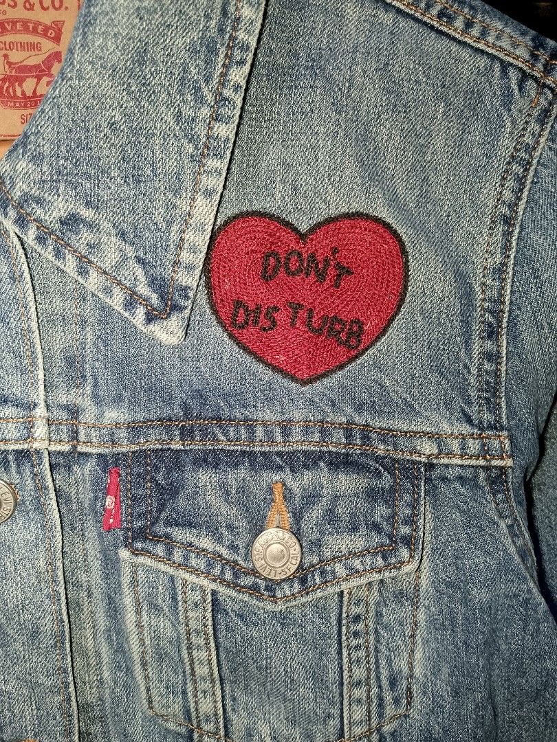 Levi's Denim Jacket Don't Disturb Patch Size XS (Category: Coats, Jackets and Outerwear) located in Manila. Submitted by mjthrifted_second (Listing ID 1465025781, Image 3). Description: - Brand: Levi's - Size: Extra Small (XS) -Dimes: 18/23 - Color: Classic Blue - Design: Embroidered red heart patch with 'DON'T DISTURB' lettering - Features: Front metal button closures, dual button-flap chest pockets, and side welt pockets - Origin: Made in Sri L