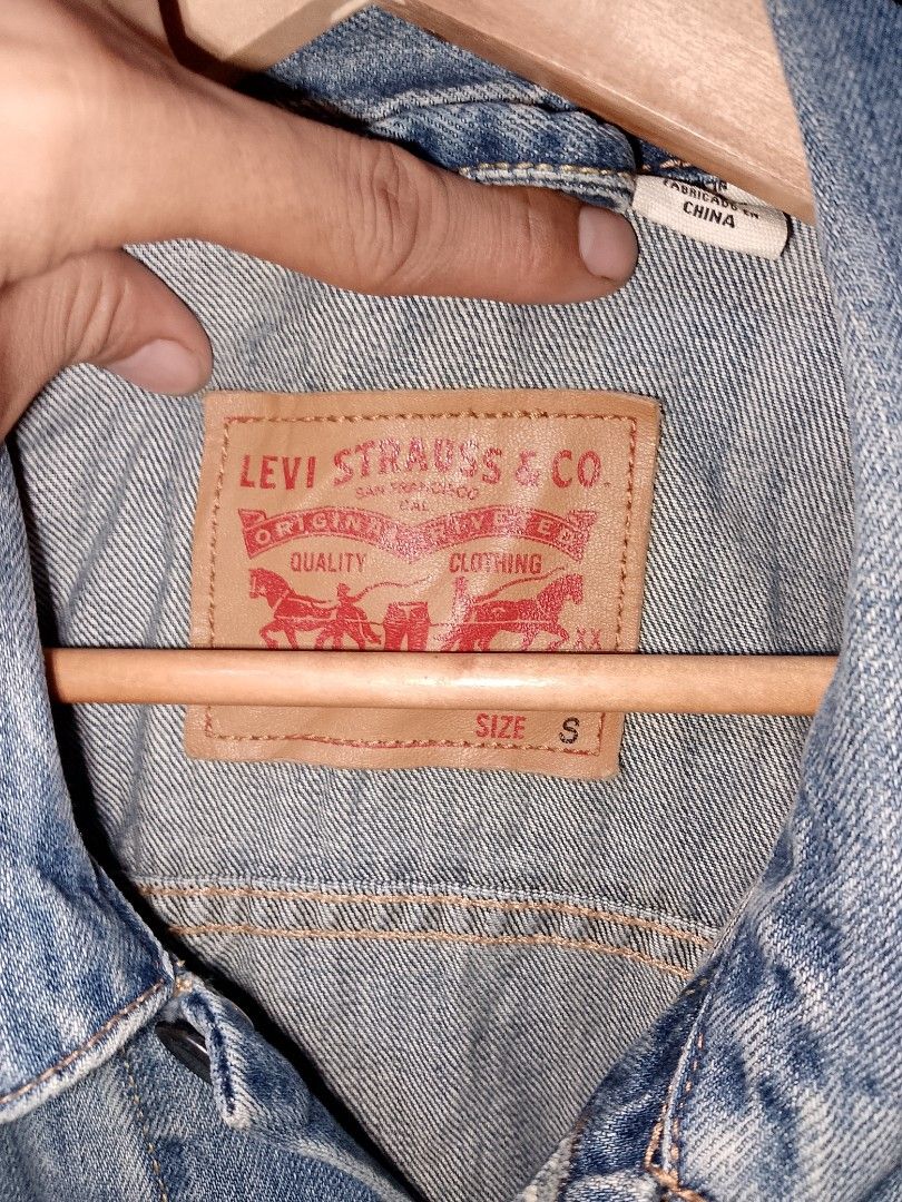 Levi's denim jacket light wash size S (Category: Coats, Jackets and Outerwear) located in Manila. Submitted by mjthrifted_second (Listing ID 1465021308, Image 2). Description: - Brand: Levi's - Wash: Light wash with natural fading - Size: Small (Relaxed fit) -Dimes: 22/26 - Features: Classic button-up front, chest flap pockets, side welt pockets, and back leather brand patch - Condition: Pre-loved with natural fading - Style: Versatile layering p