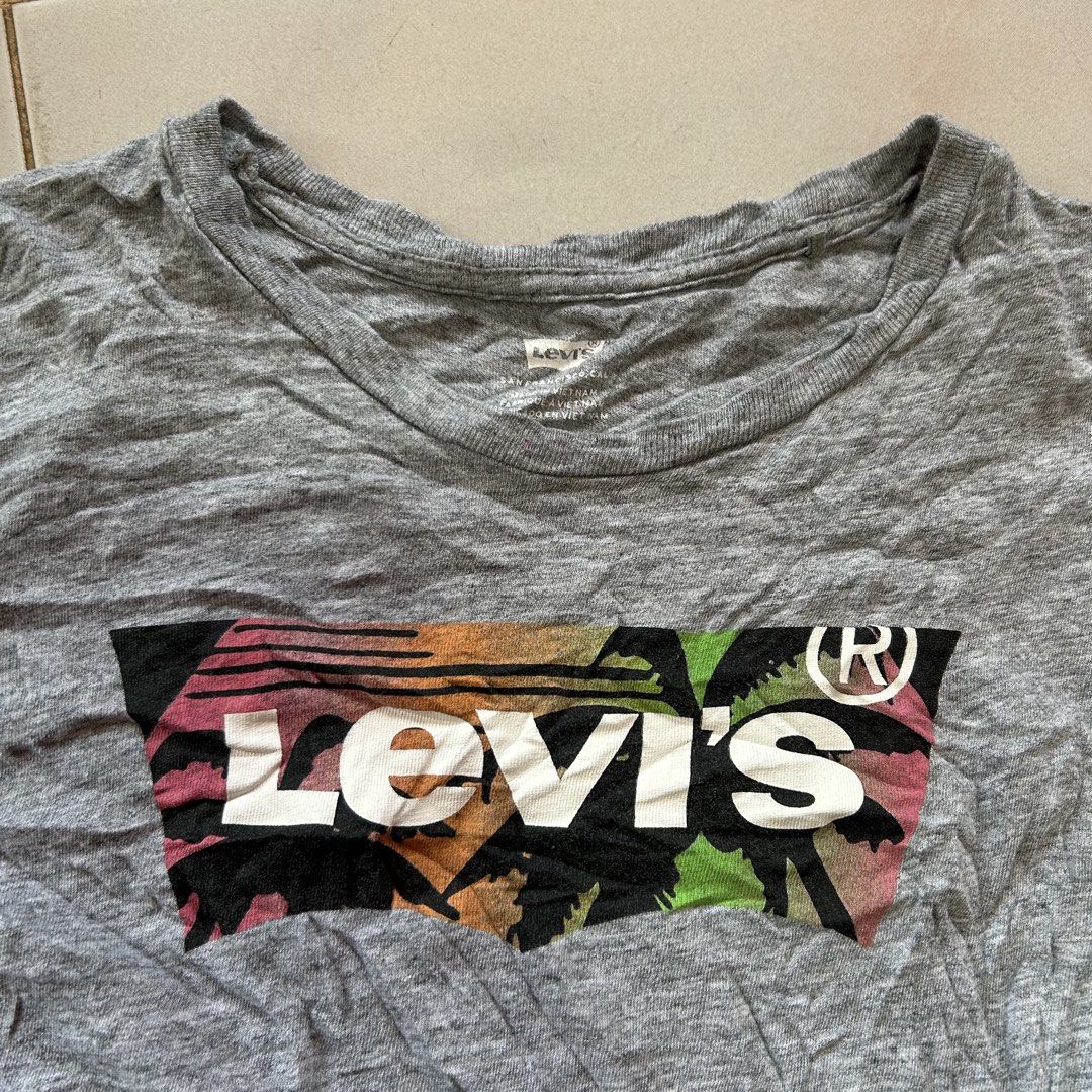 Levi's Grey Graphic T-Shirt 🥰 (Category: Shirts) located in Jinoba-an. Submitted by eegiboy (Listing ID 1465002232, Image 3). Description: - Brand: Levi's - Color: Grey with colorful palm tree graphic logo - Size: XS -small - Material: Comfortable cotton blend - Origin: Made in Vietnam - Features: Classic crew neck, short sleeves, and signature red tab on bottom hem - Condition: Great for casual everyday wear excellent condition 400plussf Dm me 