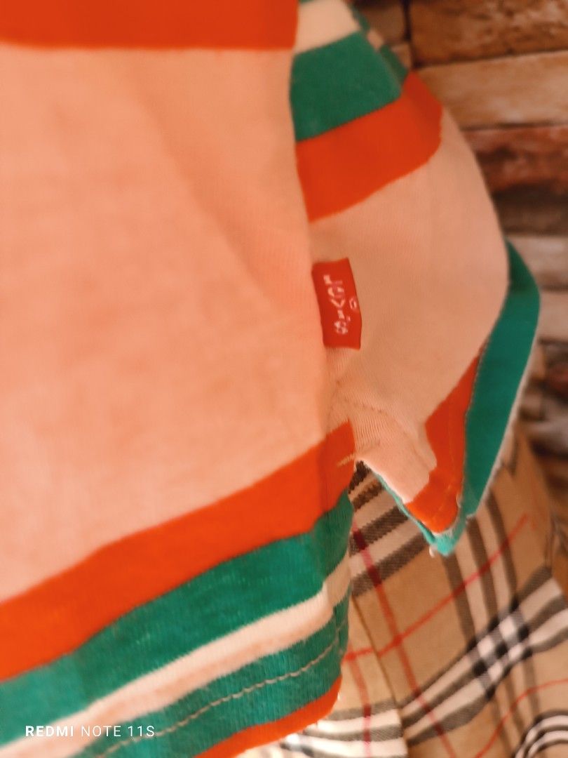Levi's Striped Polo Shirt (Category: Babies & Kids Fashion) located in Gapan. Submitted by thrift2heaven (Listing ID 1465097845, Image 2). Description: - Brand: Levi's - Style: Short-sleeve polo shirt - Color/Pattern: Pink with red and green horizontal stripes - Details: White collar with button placket, embroidered Levi's script logo on chest, and classic red tab on side seam - Size: Large - Material: Soft and comfortable cotton - Condition: Vib