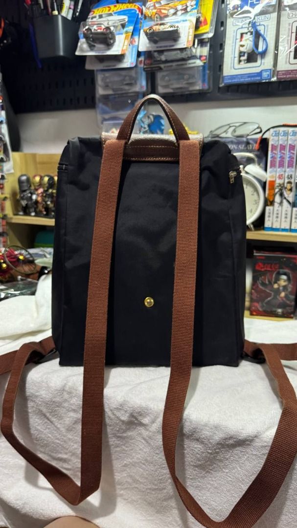 Longchamp Le Pliage Black Nylon Backpack (Category: Backpacks) located in Manila. Submitted by tmicmd1989 (Listing ID 1465047543, Image 2). Description: - Brand: Longchamp - Material: Durable black nylon with brown leather flap and handle - Hardware: Silver-tone metal with adjustable fabric shoulder straps - Closure: Front flap with snap button - Interior: Clean black lining with a convenient zip pocket and 'Longchamp Paris, Made in China' tag - 