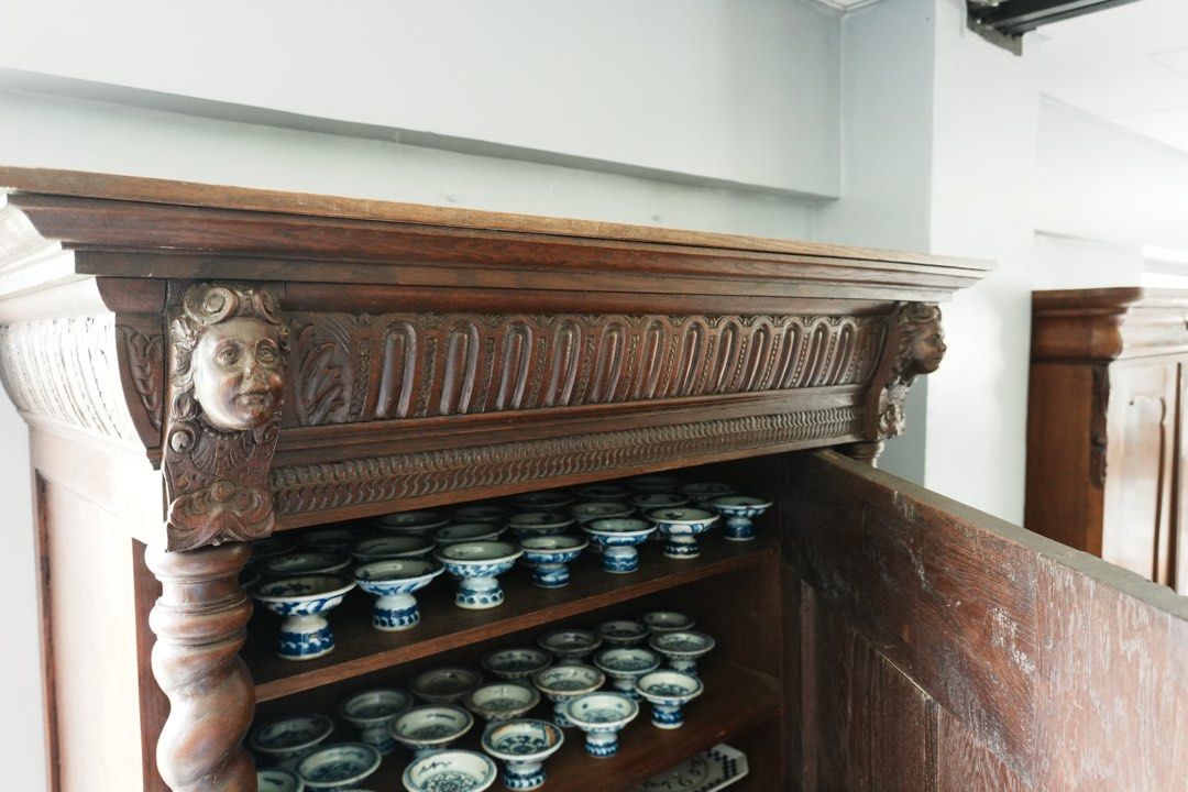 Louis XIII-Style Carved Cupboard (Category: Shelves, Cabinets & Racks) located in Manila. Submitted by heleensym (Listing ID 1464970833, Image 3). Description: An architectural wooden cupboard framed by full-height barley-twist columns and topped with a richly carved cornice featuring two expressive faces. Floral panel carving, patterned borders, and rounded bun feet complete the design. Separate upper and lower doors open to shelved storage, mak