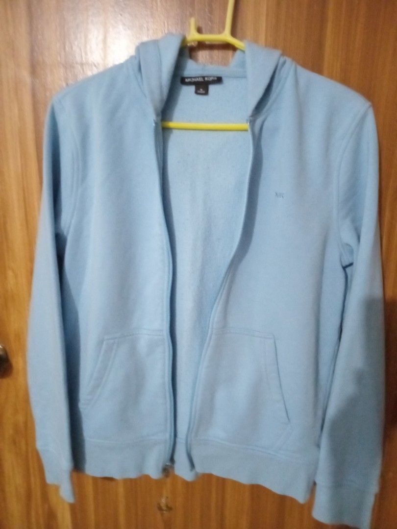 Michael Kors Light Blue Zip Hoodie (Category: Coats, Jackets and Outerwear) located in Marikina City. Submitted by joyful.finds (Listing ID 1464969451, Image 1). Description: Light blue zip-up hoodie from Michael Kors. Size medium. Soft fleece material with a front zipper and split kangaroo pockets. Hoodie attached at the neckline. Minimal branding with small embroidered letters on the chest. Ribbed cuffs and hem line. Easy to throw on for cooler