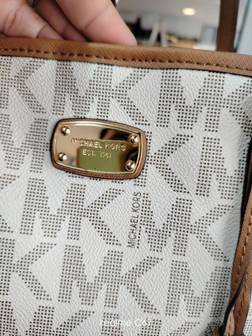 Michael Kors MK Logo Tote Bag White Brown (Category: Tote Bags) located in Bacolod City. Submitted by Mike23MattPreloved (Listing ID 1465007007, Image 3). Description: - Authentic Michael Kors tote bag - Classic white and brown monogram print - Tan leather adjustable shoulder straps with buckle details - Stylish hanging MK charm and front metal logo plaque - Elegant gold-tone hardware - Roomy cream fabric interior with repeating MK lettering - Op
