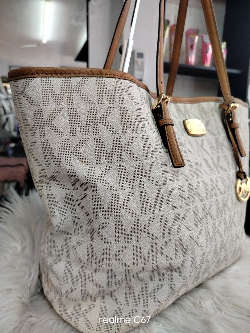 Michael Kors MK Logo Tote Bag White Brown (Category: Tote Bags) located in Bacolod City. Submitted by Mike23MattPreloved (Listing ID 1465007007, Image 2). Description: - Authentic Michael Kors tote bag - Classic white and brown monogram print - Tan leather adjustable shoulder straps with buckle details - Stylish hanging MK charm and front metal logo plaque - Elegant gold-tone hardware - Roomy cream fabric interior with repeating MK lettering - Op