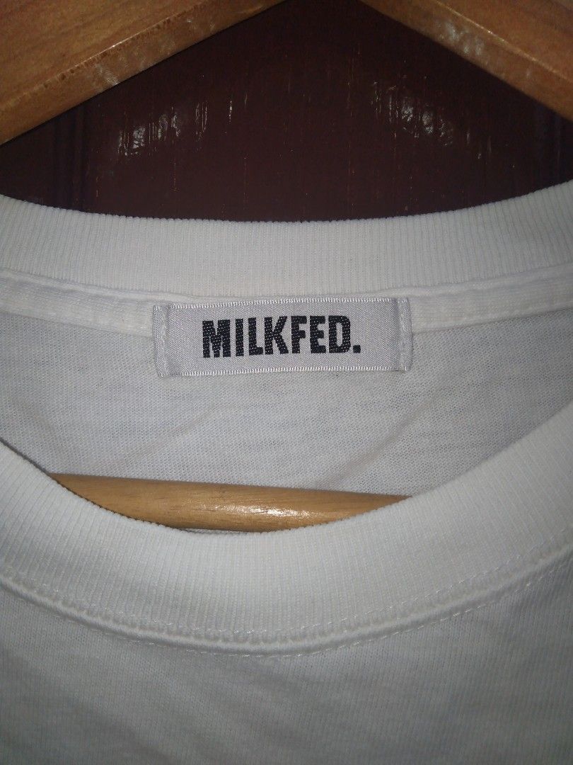Milkfed Heaven Twenty-Seven White Graphic Tee (Category: Activewear) located in Manila. Submitted by jaradhiggins24 (Listing ID 1465114885, Image 3). Description: - Brand: Milkfed - Color: White with pink graphic lettering - Design: 'MILKFED HEAVEN TWENTY-SEVEN' on front with a woven inspirational quote patch near the hem - Fit/Style: Classic crew neck, short sleeves - Size: ONE - Material: 100% cotton (standard care instructions included) - Cond