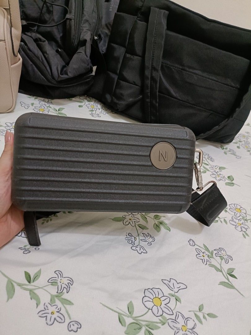 Mini Luggage Hard Shell Crossbody Bag Dark Grey (Category: Cross-body Bags) located in Manila. Submitted by yojie2026 (Listing ID 1465132598, Image 2). Description: - Color: BLACK - Design: Miniature suitcase hard shell with ribbed texture and round 'N' logo patch - Closure: Top zip closure - Strap: Adjustable black strap with silver hardware - Style: Compact and trendy, great for everyday casual wear.