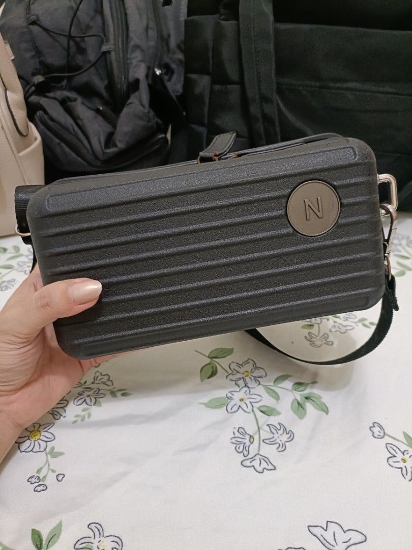Mini Luggage Hard Shell Crossbody Bag Dark Grey (Category: Cross-body Bags) located in Manila. Submitted by yojie2026 (Listing ID 1465132598, Image 1). Description: - Color: BLACK - Design: Miniature suitcase hard shell with ribbed texture and round 'N' logo patch - Closure: Top zip closure - Strap: Adjustable black strap with silver hardware - Style: Compact and trendy, great for everyday casual wear.