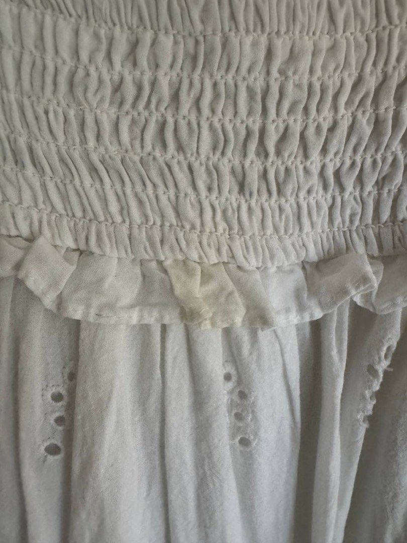 MNG White Smocked Eyelet Top XS (Category: Blouses) located in Taguig. Submitted by anxmz (Listing ID 1465043737, Image 2). Description: - Brand: MNG - Size: XS (EUR XS, USA 2) - Material: Lightweight cotton - Design: Smocked bodice with ruffle trim and eyelet embroidery - Flaw: Noticeable yellow stain on the ruffled edge near the smocked section.