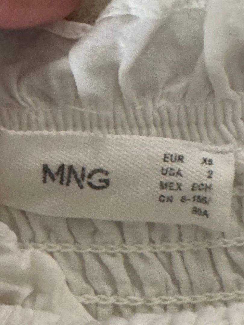 MNG White Smocked Eyelet Top XS (Category: Blouses) located in Taguig. Submitted by anxmz (Listing ID 1465043737, Image 3). Description: - Brand: MNG - Size: XS (EUR XS, USA 2) - Material: Lightweight cotton - Design: Smocked bodice with ruffle trim and eyelet embroidery - Flaw: Noticeable yellow stain on the ruffled edge near the smocked section.