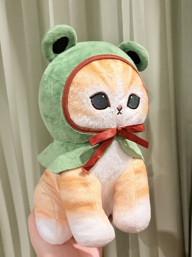 Mofusand Frog Cat Plush Toy Parade (Category: Plushies & Soft Toys) located in Caloocan City. Submitted by miffuph (Listing ID 1465127427, Image 2). Description: - Authentic Mofusand cat plush with official Parade tag - Wears an adorable green frog costume with a red ribbon under the chin - Features orange tabby markings on the head, body, and tail - Made with ultra-soft fabric for hugging - Detailed with cute white paws and pink beans underneath