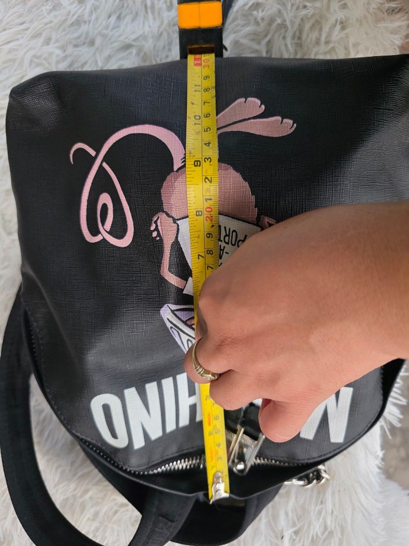 Moschino Rat-A-Porter Backpack Black (Category: Backpacks) located in Lemery. Submitted by venus23 (Listing ID 1465095508, Image 3). Description: - Brand: Moschino - Style: Rat-A-Porter Backpack - Color: Black with striking white branding & cartoon rat print - Material: Durable Saffiano-style textured finish - Hardware: Silver-tone Moschino Milano stamped zips with chain handle detail - Size: Practical everyday size, approx. 11 inches across - Co