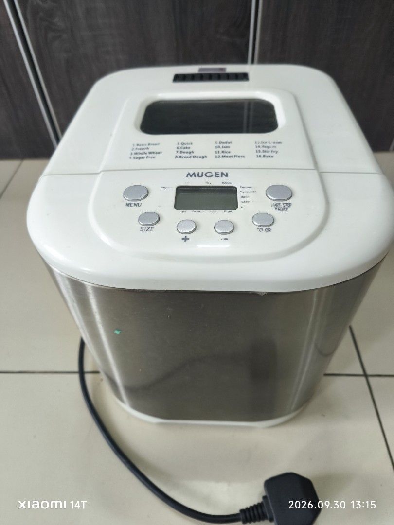 Mugen Automatic Bread Maker Machine (Category: Breadmakers) located in Shah Alam. Submitted by zaharein (Listing ID 1465008449, Image 1). Description: - Brand: Mugen XBM-6000 1kg Automatic Bread Maker - Design: Stainless steel body with a white top lid and digital control panel - Versatile Functions: Multiple menu options including basic bread, cake, dough, jam, and yogurt - Included Accessories: Non-stick baking pan and kneading paddle - Power: 