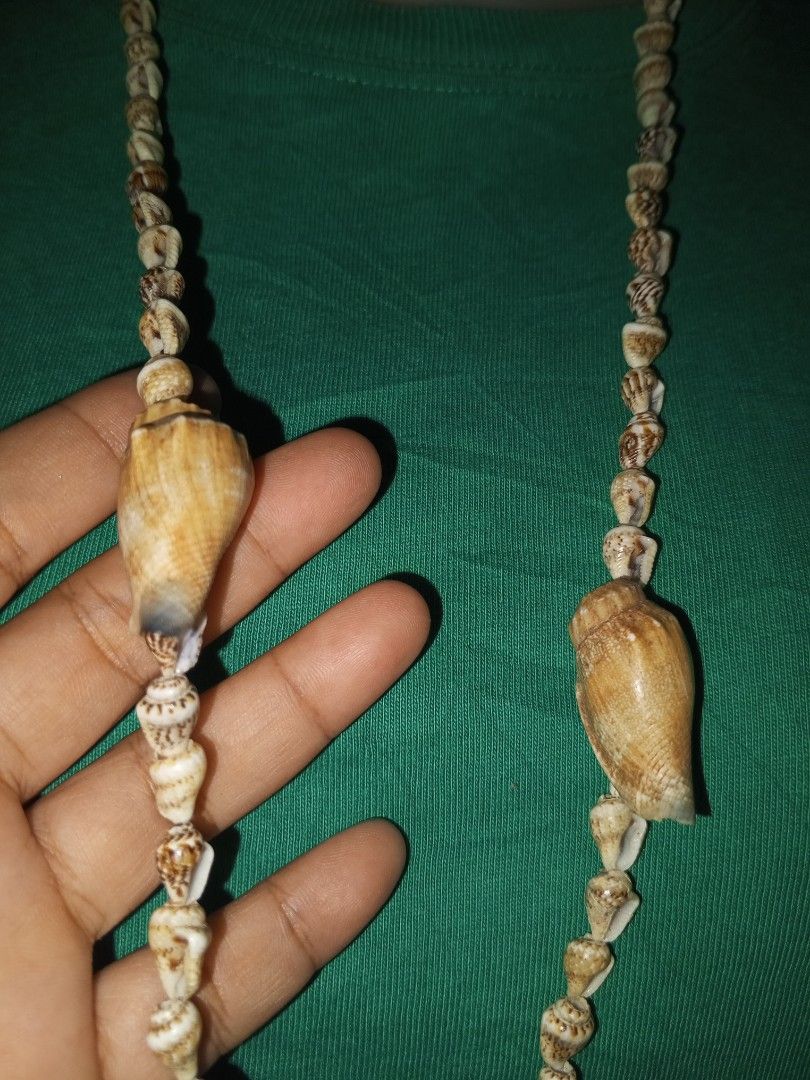 Natural seashell beaded necklace with warning tags (Category: Necklaces) located in Magalang. Submitted by zeiansoria64090 (Listing ID 1464980387, Image 3). Description: - Long seashell necklace that hangs down the chest - Features a mix of various brown and white shells - Accented with multiple larger shell accents throughout the strand - Perfect earthy beach-style accessory for summer outfits - Warning: Contains small parts, choking hazard labe