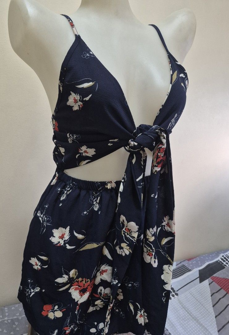 Navy Floral Cutout Tie-Front Romper (Category: Rompers) located in Pasig City. Submitted by ces.maranan16 (Listing ID 1465071587, Image 2). Description: - Navy blue romper with an all-over white and red floral print - Deep V-neckline with a cute tie-front detail and trendy waist cutouts - Thin adjustable spaghetti straps for a custom fit - Back elastic waistband for all-day comfort - Lightweight fabric ideal for warm weather and beach getaways.
