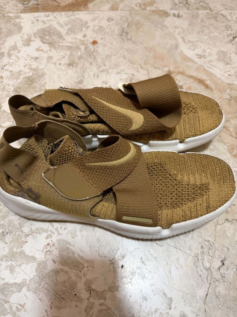 Nike Free Flyknit Sandal Gold (Category: Sneakers) located in Quezon City. Submitted by cms1116 (Listing ID 1465102080, Image 2). Description: - Brand: Nike - Model: Free Slip-On - Colorway: Gold with white Nike Free sole - Design: Unique cross-strap detail on top and heel - Material: Lightweight knit upper with flexible running-style sole - Condition: Wear and discoloration present throughout the fabric, with noticeable dark staining on the heel