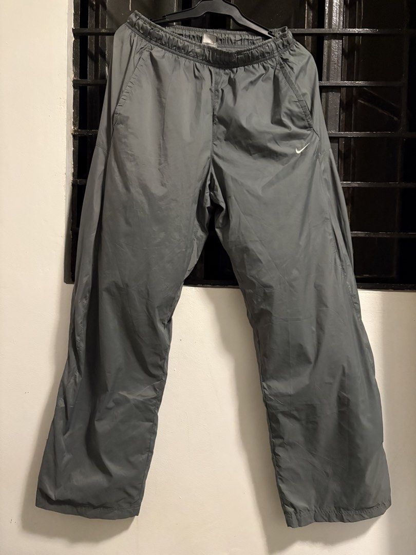 Nike Grey Nylon Track Pants Size L (Category: Joggers) located in Pakil. Submitted by lucii_4 (Listing ID 1465163431, Image 3). Description: - Brand: Nike - Item: Track Pants - Color: Grey - Size: Large (L) - Material: 100% nylon outer with polyester lining - Fit: Elastic waistband with adjustable drawstring - Pockets: Convenient zipper pocket on the back right side - Details: Small white Nike swoosh logo on front left thigh - Origin: Made in Vie