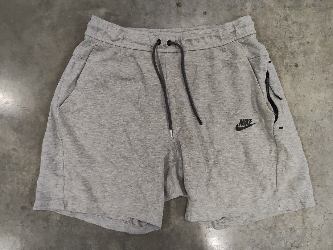 Nike Grey Tech Fleece Shorts Size M (Category: Shorts) located in Manila. Submitted by jepoy2026 (Listing ID 1465101083, Image 1). Description: - Brand: Nike - Color: Grey - Size: Medium (Tag: 80cm waist, 165-175cm height) - Material: Comfortable cotton and polyester blend - Waistband: Adjustable with black drawstrings - Storage: Convenient side zippered pocket on the left leg - Branding: Nike logo printed near the hem - Condition: Clean and well