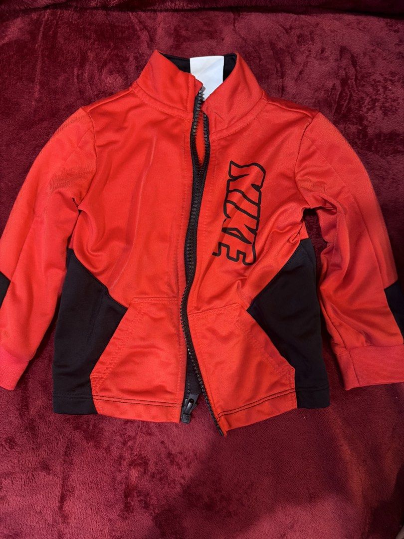 Nike Red Black Zip Up Jacket Kids 18M (Category: Babies & Kids Fashion) located in Manila. Submitted by karlaaricheta (Listing ID 1465080961, Image 1). Description: - Brand: Nike - Color: Red and black - Size: 18 months (80-86 cm) - Design: Stand collar, full front zip, vertical Nike lettering on chest, and two front pockets - Material: Soft athletic fabric - Condition: Excellent pre-loved condition - Perfect for sporty everyday wear.