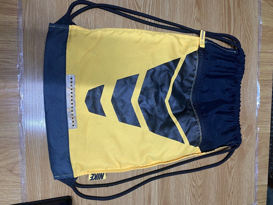 Nike yellow and black drawstring gym bag (Category: Backpacks) located in Marikina City. Submitted by unknownus.eri (Listing ID 1465073157, Image 1). Description: - Authentic Nike drawstring bag in a vibrant yellow and black colorway - Features a stylish chevron graphic on the front - Convenient side zipper pocket for small essentials - Built-in reflective strip detail for safety and visibility - Durable black drawstrings that double as shoulder 