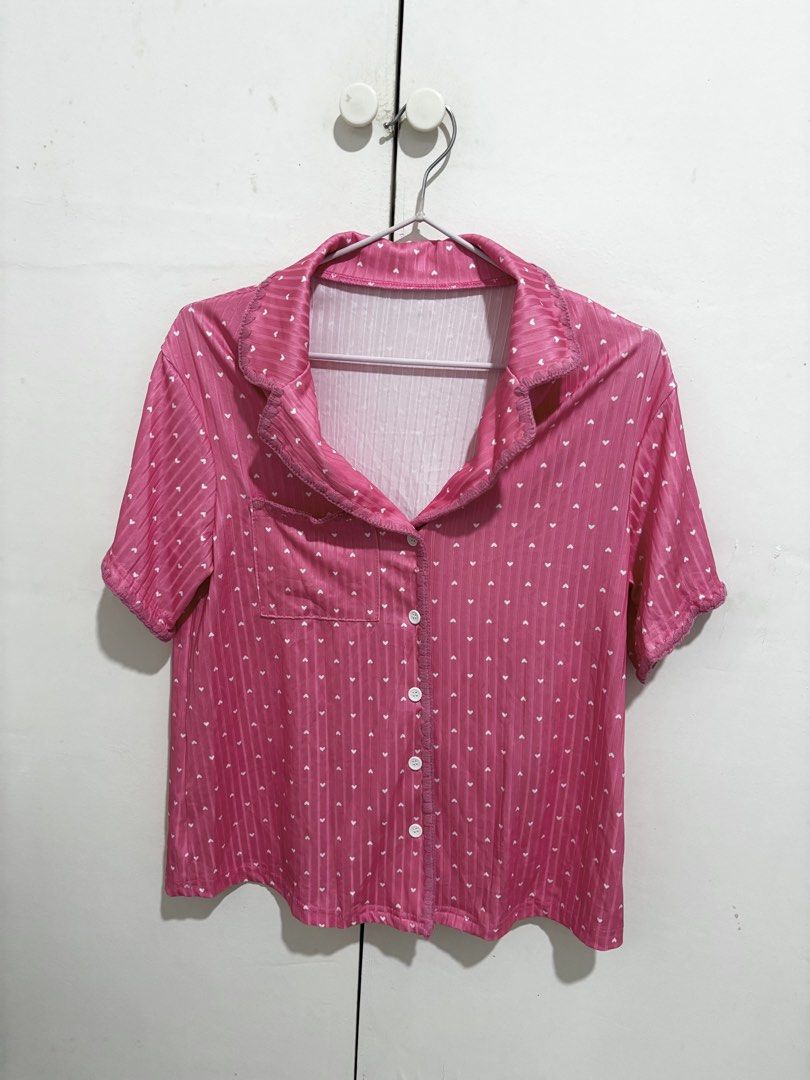 Pink Heart Pattern Short Sleeve Pajama Top (Category: Undergarments & Loungewear) located in Manila. Submitted by dianafayesimbre (Listing ID 1465073668, Image 3). Description: - Color/Pattern: Pink with white mini hearts - Material/Texture: Vertical ribbed texture - Design: Collared neckline, front button closure, small chest pocket - Fit: Relaxed fit for lounging or sleeping - Condition: Clean, ready to wear - Size S on tag but can fit up to se