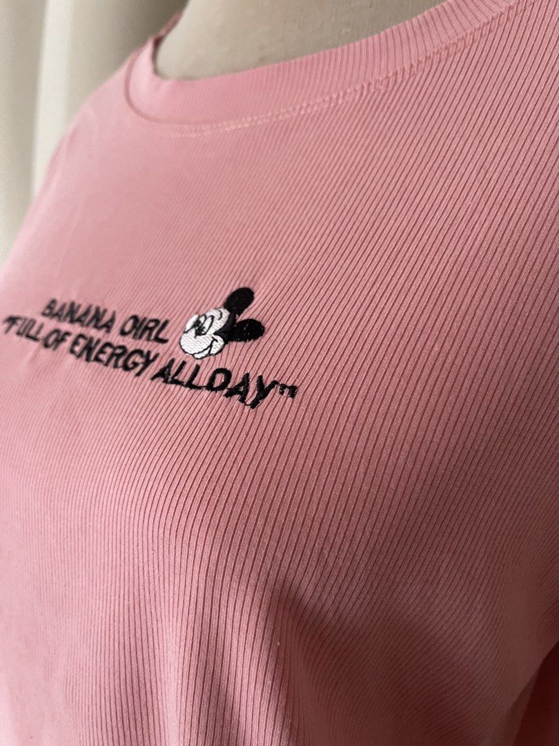 Pink ribbed cotton semi crop embroid (Category: Shirts) located in Cainta. Submitted by zlove111 (Listing ID 1464969834, Image 2). Description: - Color: Pink - Material: Soft and comfortable knit fabric - Design: Ribbed texture with cute lettuce hem details on sleeves and bottom - Graphic: Mickey Mouse face with 'BANANA GIRL "FULL OF ENERGY ALLDAY"' chest embroidery - Neckline: Classic round ribbed neckline - Fit: Casual everyday top, easy to sty
