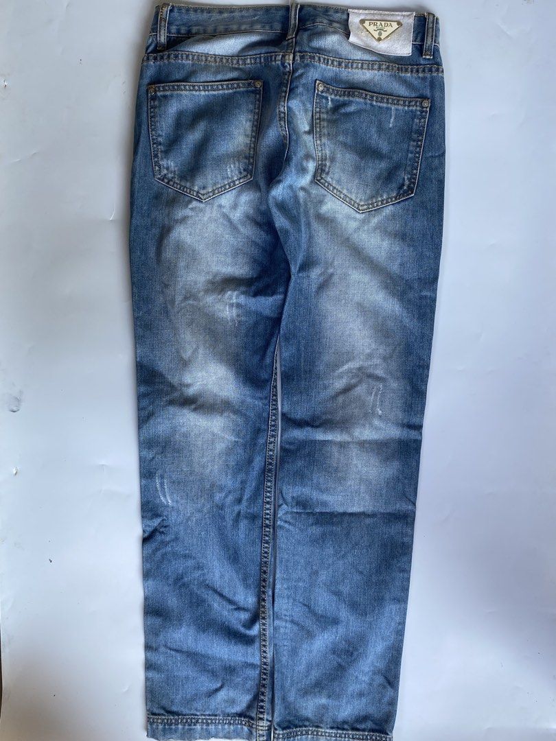 Prada Distressed Denim Jeans (Category: Jeans) located in Manila. Submitted by deguertoje73072 (Listing ID 1465008919, Image 3). Description: - Brand: Prada - Wash: Light wash with factory distressing and whiskering - Fit: Straight leg - Details: Iconic triangular Prada logo patch on the back waistband, branded buttons and rivets - Pockets: Classic five-pocket design - Hem: Double-stitched hems - Condition: Great staple piece for casual outfits.