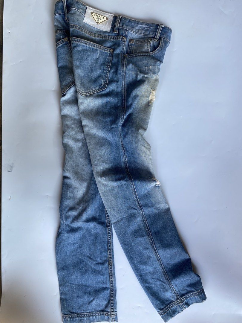 Prada Distressed Denim Jeans (Category: Jeans) located in Manila. Submitted by deguertoje73072 (Listing ID 1465008919, Image 1). Description: - Brand: Prada - Wash: Light wash with factory distressing and whiskering - Fit: Straight leg - Details: Iconic triangular Prada logo patch on the back waistband, branded buttons and rivets - Pockets: Classic five-pocket design - Hem: Double-stitched hems - Condition: Great staple piece for casual outfits.