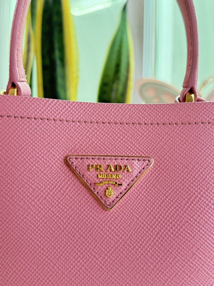 Prada Pink Saffiano Leather Bucket Bag (Category: Luxury Bags & Wallets) located in Cainta. Submitted by thekikaymachine (Listing ID 1465132913, Image 3). Description: - Brand: Prada - Material: Soft pink Saffiano leather - Hardware: Gold-tone - Design: Structured vertical shape with iconic metal triangle logo - Straps: Top handle and detachable, adjustable shoulder strap - Includes: Original prada dustvag - Condition: Clean lines, everyday size,