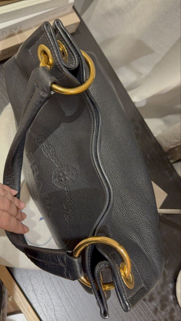 Prada Vitello Daino Embossed Logo Hobo (Category: Luxury Bags & Wallets) located in Quezon City. Submitted by mamadeclutter8877 (Listing ID 1465092809, Image 3). Description: - Authentic Prada shoulder bag in black grained leather - Features a large embossed logo on the front and classic enamel triangle logo on the side - Elegant gold-tone hardware rings - Comfortable single rounded leather handle - Slouchy, spacious interior perfect for daily es