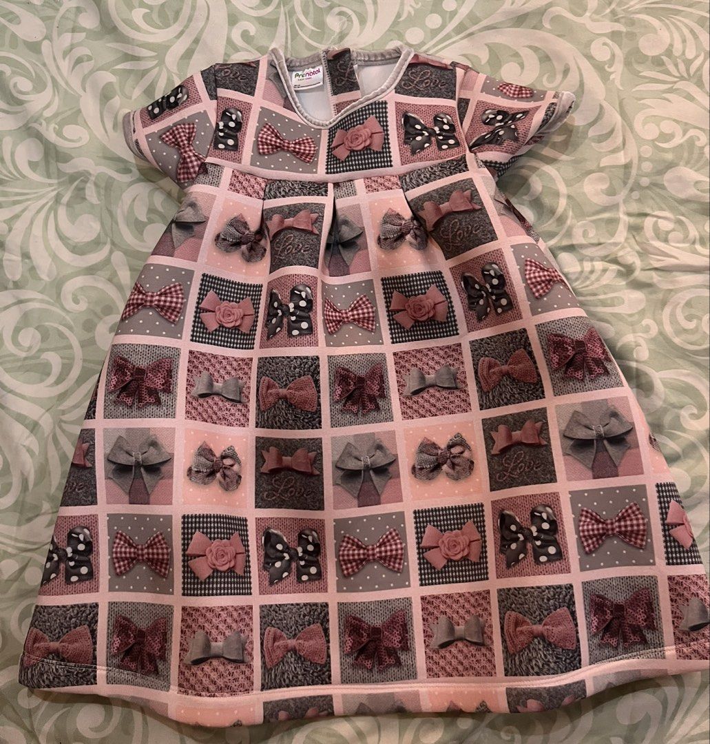Prénatal Easy Chic Bow Pattern Toddler Dress Size 96cm (Category: Babies & Kids Fashion) located in Batangas. Submitted by gavsandrix (Listing ID 1465048667, Image 1). Description: - Brand: Prénatal Easy Chic - Size: 96cm (fits ages 24 to 36 months) - Design: Soft pink background with grey, black, and red square pattern blocks featuring various bow designs - Features: Short sleeves, flared skirt silhouette, and a convenient small loop closure at 