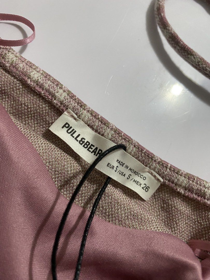 Pull&Bear Pink Plaid Mini Dress Size S NWT (Category: Dresses) located in Vigan. Submitted by wrenessie (Listing ID 1465155827, Image 3). Description: - Brand: Pull&Bear - Condition: Brand new with original store tags - Size: EUR S / USA S / MEX 26 - Design: Pink and white plaid pattern, bodycon fit, straight hem - Details: Thin spaghetti straps, sweetheart neckline, and center front fabric rosebud accent - Lining: Fully lined inside.