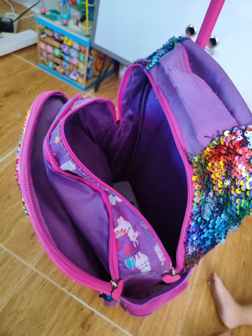 Purple Llama Rolling Backpack with Sequins (Category: Backpacks) located in Makati City. Submitted by cess_preloved (Listing ID 1464977012, Image 3). Description: - Color: Purple - Design: Cute llama with glasses, cactus prints, and 'NO DRAMA LLAMA' text - Feature: Reversible color-changing sequins on the top flap - Storage: Multiple zipped compartments for books and gear - Mobility: Retractable pink handle and smooth wheels for easy rolling - Ve