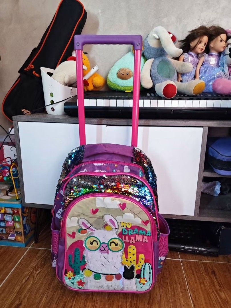 Purple Llama Rolling Backpack with Sequins (Category: Backpacks) located in Makati City. Submitted by cess_preloved (Listing ID 1464977012, Image 2). Description: - Color: Purple - Design: Cute llama with glasses, cactus prints, and 'NO DRAMA LLAMA' text - Feature: Reversible color-changing sequins on the top flap - Storage: Multiple zipped compartments for books and gear - Mobility: Retractable pink handle and smooth wheels for easy rolling - Ve