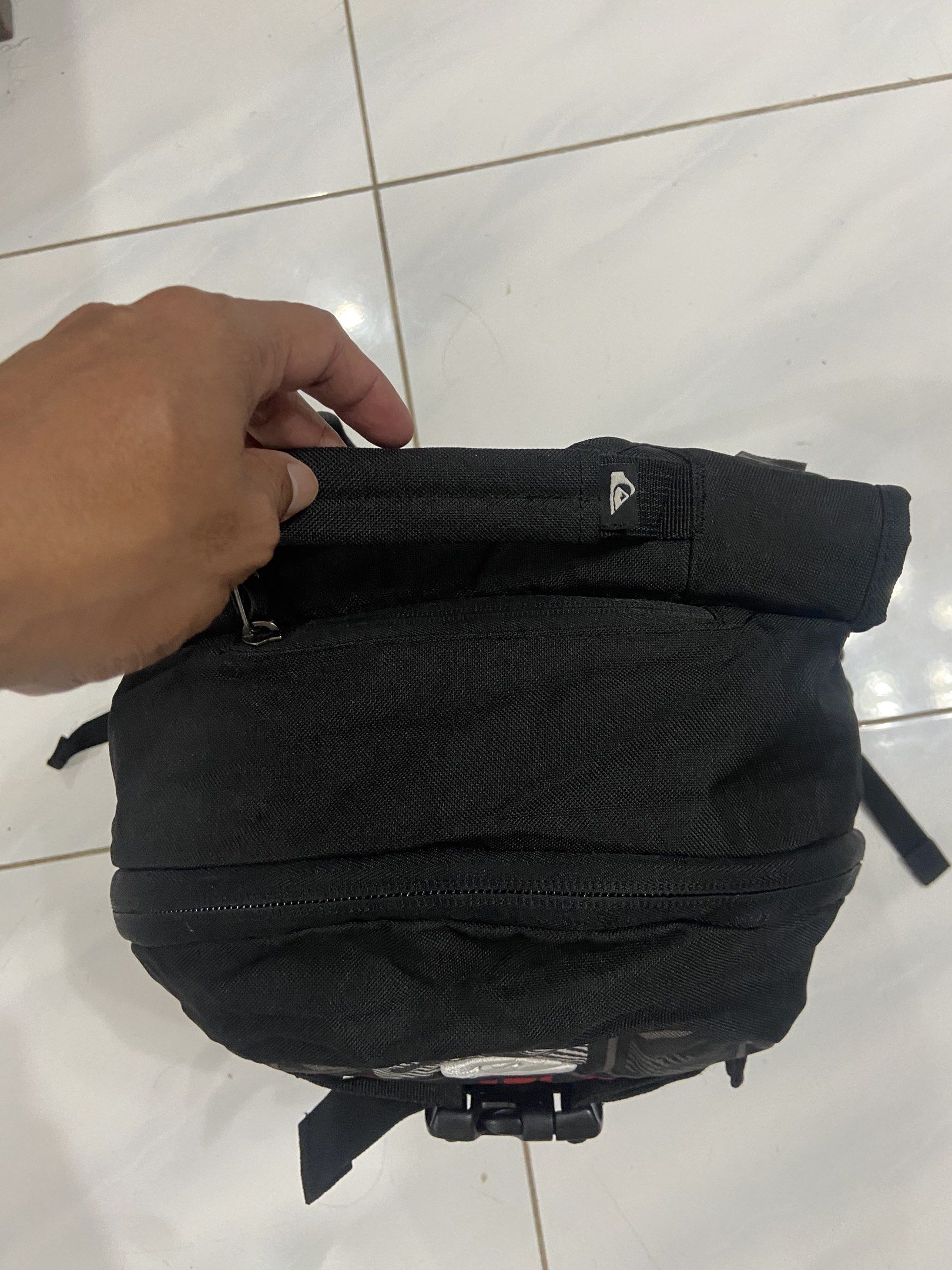 Quiksilver Backpack Black Red Pattern (Category: Backpacks) located in Pilar. Submitted by romeoabejo54125 (Listing ID 1464984428, Image 2). Description: - Brand: Quiksilver - Color: Black with red and grey geometric pattern - Compartments: Dual main compartments and side zippered pockets - Comfort: Padded shoulder straps, sternum strap, and mesh back panel - Features: Two vertical buckle straps on the front panel - Ideal for: Daily school use or