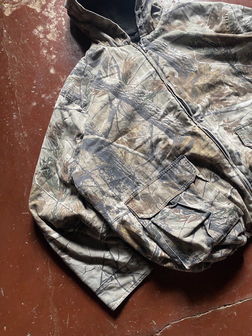 Realtree Camo Zip-Up Hooded Jacket (Category: Coats, Jackets and Outerwear) located in Manila. Submitted by dripxthrift0912 (Listing ID 1464990145, Image 3). Description: - Authentic Realtree tree and leaf camo pattern - Heavy-duty thick canvas exterior for durability - Warm black thermal lining inside - Attached hood for extra weather protection - Two large front cargo pockets with secure flap closures - Ideal for outdoor activities or rugged ca