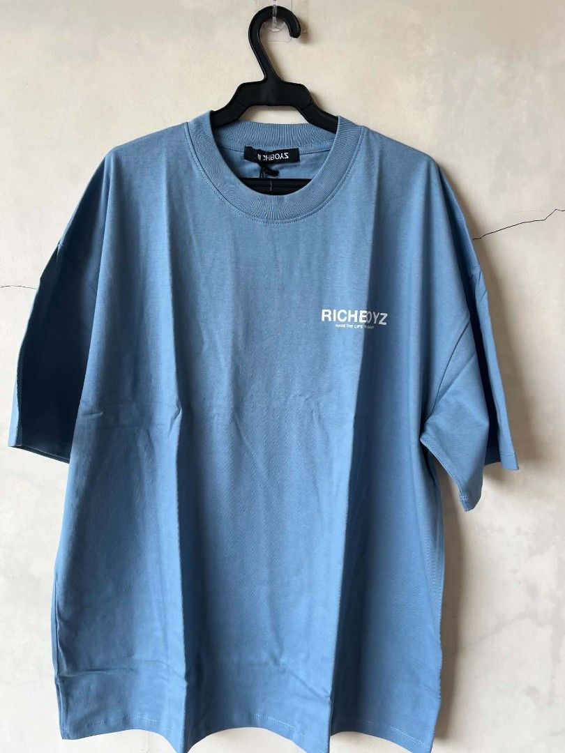 RICHBOYZ Blue Graphic Oversized T-shirt (Category: Tshirts & Polo Shirts ) located in Iloilo. Submitted by franzventures (Listing ID 1464971360, Image 1). Description: - Brand: RICHBOYZ - Color: Light blue - Fit: Oversized streetwear cut - Details: Small text print on chest, large white RICHBOYZ lettering on back - Neckline/Sleeves: Crew neck with short sleeves - Condition: Excellent, clean fabric with no stains or fading.