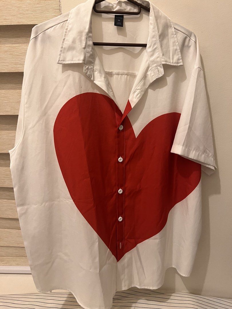 Romwe White Red Heart Button Down Short Sleeve Shirt M (Category: Shirts) located in Las Pinas. Submitted by basicapparel_mnl (Listing ID 1465104016, Image 1). Description: - Brand: Romwe - Style: White button-down shirt with short sleeves and collared neck - Design: Eye-catching large red heart graphic on the front - Size: Medium (M) - Condition: Good - Perfect for: Casual wear, streetwear, and playful outfits.