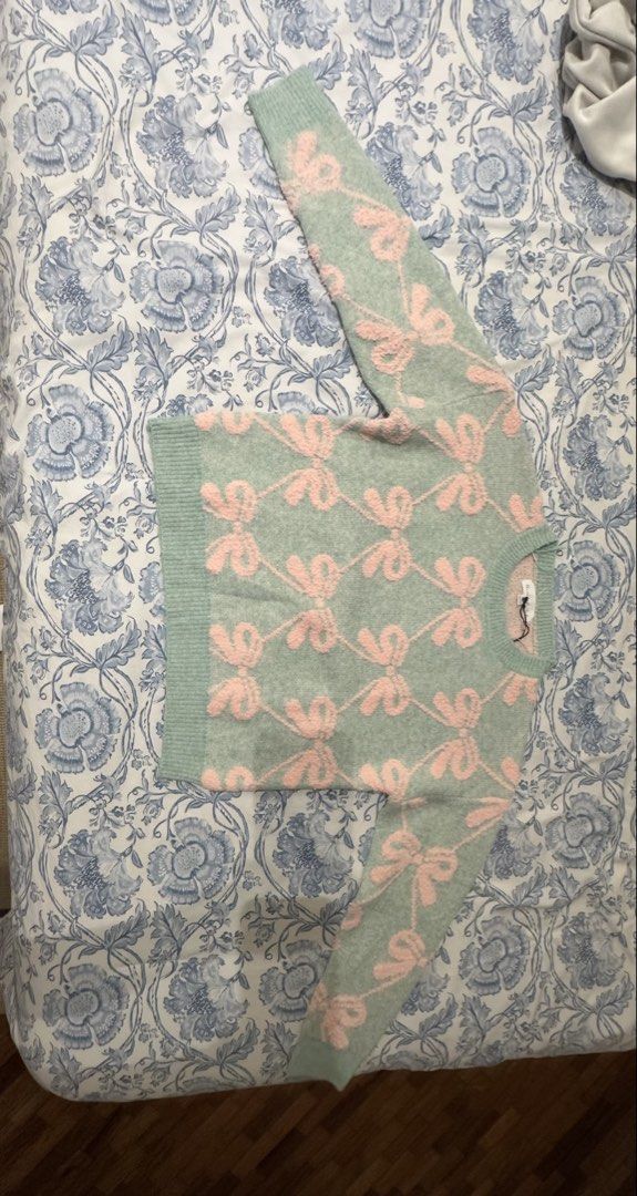 Sage Green and Pink Bow Pattern Knit Sweater (Category: Coats, Jackets and Outerwear) located in Manila. Submitted by cocoomelooonnnn (Listing ID 1465078252, Image 2). Description: - Color & Pattern: Sage green with a repeating pink bow diamond grid - Material: Soft, fuzzy texture for maximum warmth and comfort - Details: Ribbed crew neckline, cuffs, and hem - Condition: Brand new with tag still attached - Styling: Easy pullover style that pairs 